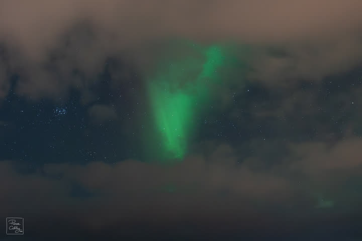 Green aurora breaking through the clouds