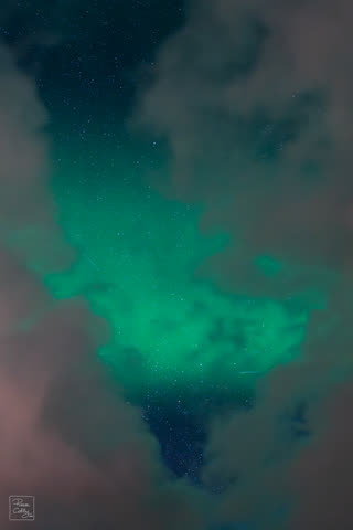 Green aurora glowing through a gap in the clouds