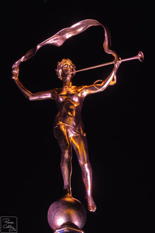 Golden statue of a trumpeter against a black background, Brussels