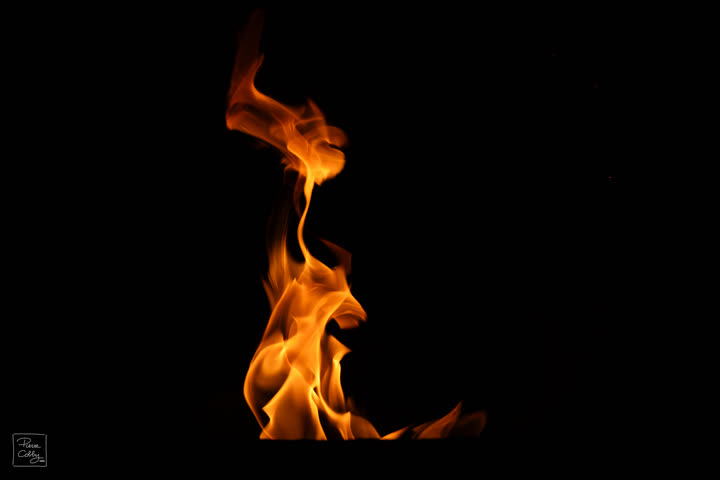 Thin orange flame curling upwards on a black background