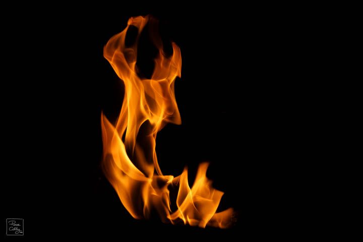 Tall orange flame frozen in motion on a black background