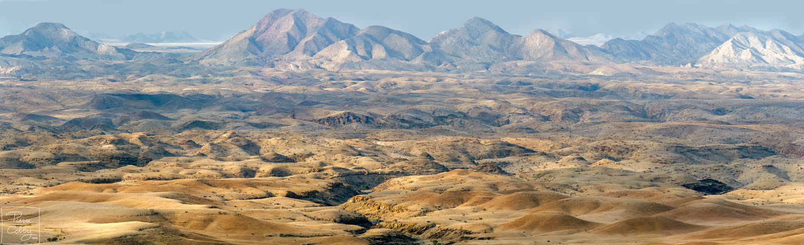 Panorama of rolling desert hills and distant mountains