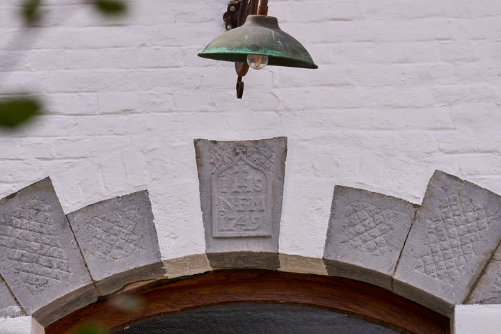 Carved stone arch with a dated keystone on the whitewashed facade