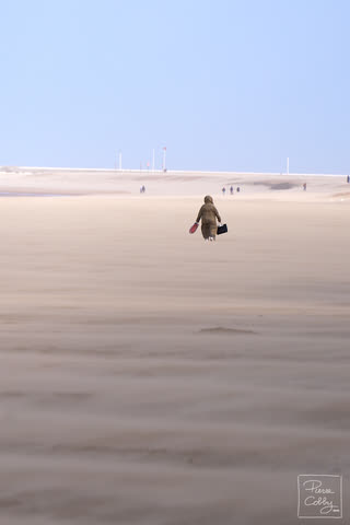 Lone walker crossing a wide, windy beach in Ostend