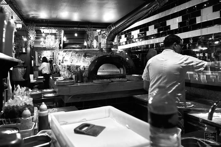 Pizza chef at work in front of a wood-fired oven in a restaurant kitchen